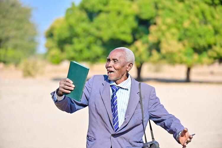A elderly man celebrating seeing and holding the Kwamashi New testament Bible for the first time